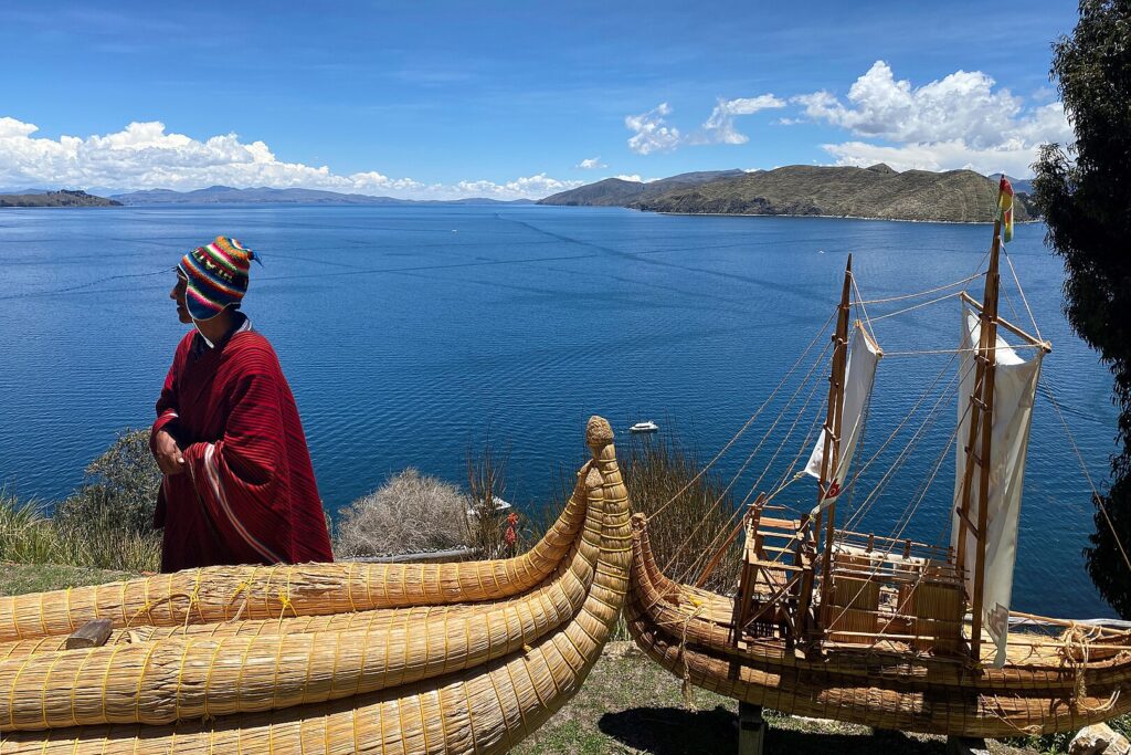 An Aymara man next to a boat made from totora at Lake Titicaca, Bolivia