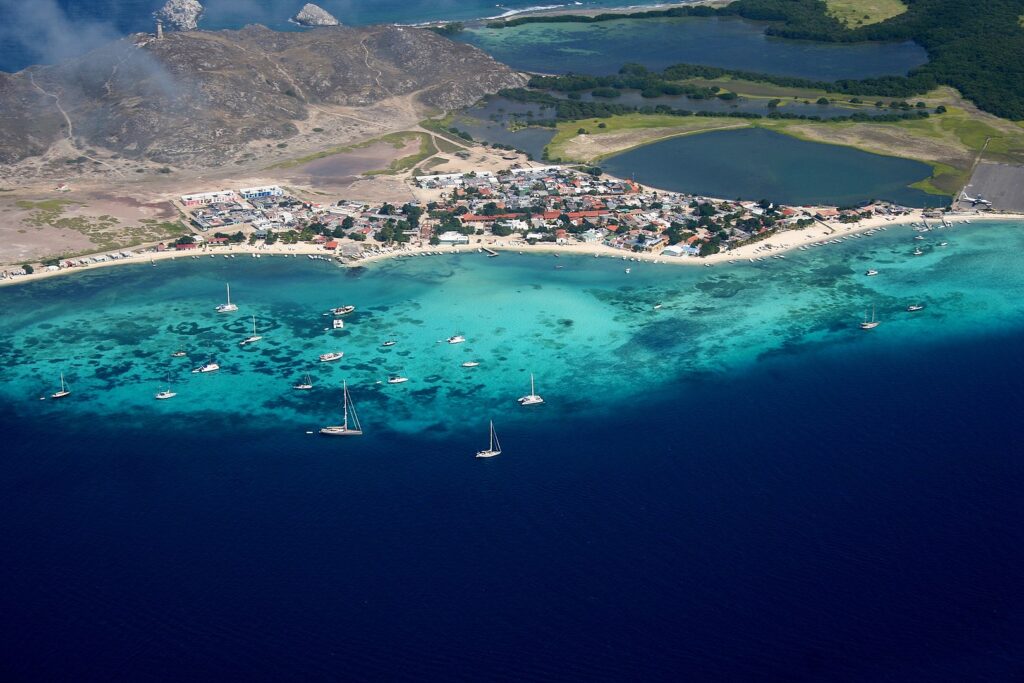 Aerial view of the Gran Roque village, the largest settlement of the Los Roques archipelago (Venezuela). On the upper left corner of the image, El Faro Holandés (The Dutch Lighthouse, built between 1870 and 1880) is visible. Aerial view of the Gran Roque village, the largest settlement of the Los Roques archipelago (Venezuela). On the upper left corner of the image, El Faro Holandés (The Dutch Lighthouse, built between 1870 and 1880) is visible.